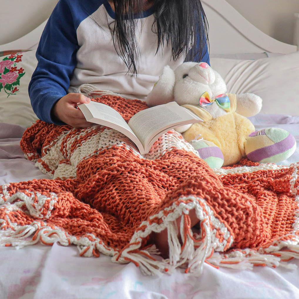 A women warp in An Orange knitted summer blanket for babies from eri silk -  Download this beautiful silk knitting pattern online from Muezart India 