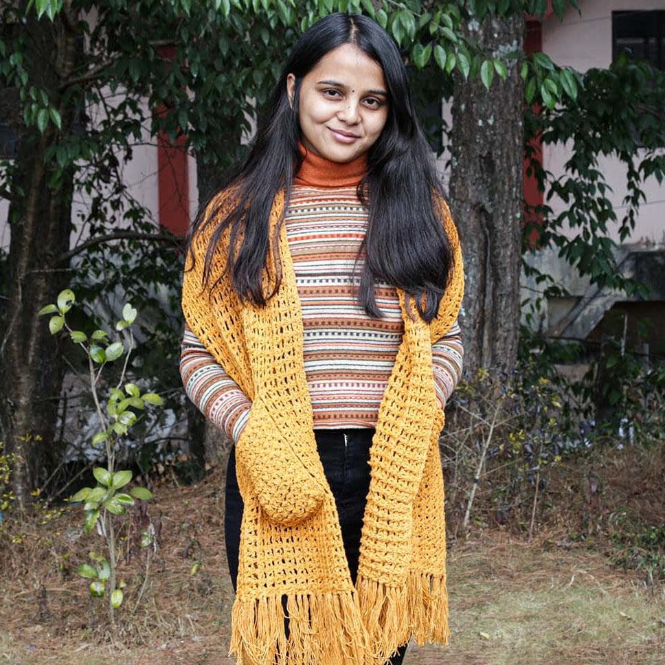 A Women wearing a yellow crochet silk scarf from eri silk -  Download this beautiful silk crochet pattern online from Muezart