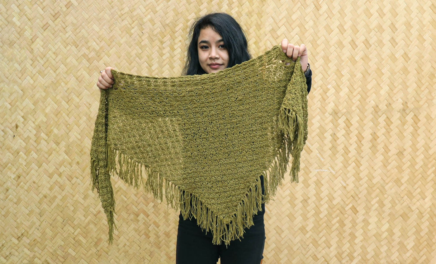 A Women holding a green knitted silk scarf from eri silk -  Download this beautiful silk knitting pattern online from Muezart