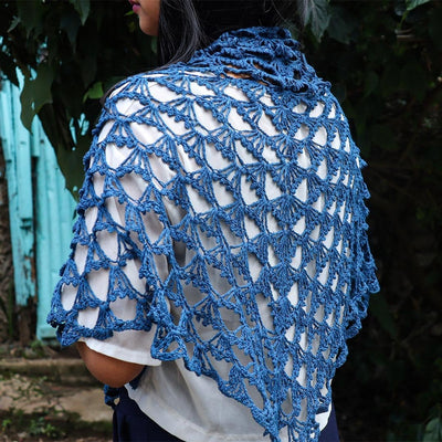 A Women wearing a blue knitted silk scarf from eri silk -  Download this beautiful silk knitting pattern online from Muezart